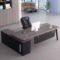 Bureau de direction moderne noir et blanc contrasté avec pieds métalliques inclinés, passe-câbles rond, armoire latérale, table de PDG/directeur
