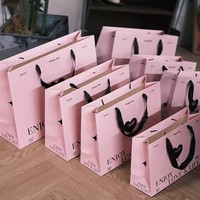 Élégantes boîtes cadeaux en papier rose avec ruban satiné et sac de transport pour vêtements féminins et solutions d'emballage pour bougies
