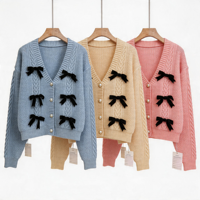 Cardigan court en maille tricotée nid d'abeille bleu clair avec nœud en velours noir et boutons perlés pour femme