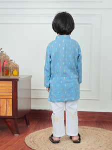 Lindo niño pequeño con kurta azul estampada y pijama blanco, sonriendo mientras se encuentra en el interior de una casa, con un atuendo étnico tradicional indio. - Product Image 2