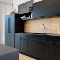 Meubles de cuisine modernes bicolores avec îlot en bois clair, portes plates noires et rangement intégré pour appareils électroménagers