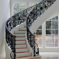 Escalier incurvé élégant en fer forgé sur mesure pour le hall d'entrée de la villa ferronnerie artistique et marches en bois