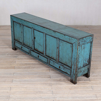 Armoire de rangement en bois massif vieilli et patiné pour un salon de style rétro et vintage, meuble de présentation pour maison d'hôtes.