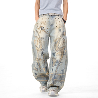 Jean vintage délavé coupe large avec broderie abstraite, œillets métalliques, effet usé et bords effilochés, style streetwear ample
