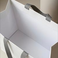Sac cadeau en carton ivoire écologique, biodégradable, recyclable et réutilisable, avec logo argenté gaufré, poignées en ruban résistantes et pelliculage mat