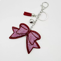 Koningsblauwe modieuze sleutelhanger met zwarte achtergrond, strikvorm, volledig bezet met strass steentjes en kwastjes, best verkochte charme hangende ornament