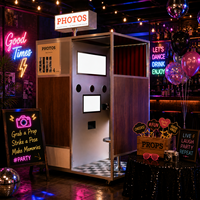 Machine à photos de type photomaton rétro en bois avec enseigne néon pour bars, discothèques, soirées et événements, compatible avec les smartphones et les iPad