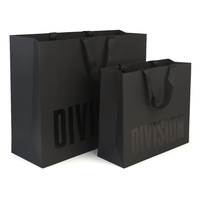 Sac en papier couché recyclable de luxe noir et or personnalisé avec poignée en ruban et pelliculage pour l'emballage de vêtements