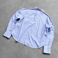 Chemise boutonnée pour homme, coupe ample, style preppy streetwear, à manches longues, avec logo personnalisé, rayures fines bleues et blanches, ourlet court et broderie.