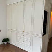 Villa élégante de style italien, bureau de maquillage intégré en MDF couleur crème, armoire-penderie avec porte vitrée cintrée du sol au plafond.