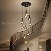 Lustre en cascade avec globes en verre gris fumé, ampoules dorées, cordons noirs, en fer et verre, éclairage moderne et élégant pour escalier de villa