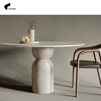 Table à manger ronde en travertin beige élégante de nouvelle conception Tostone avec pieds en forme de sablier pour les espaces à manger sophistiqués