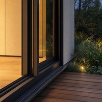Maison en structure acier portable avec intérieur lumineux, fenêtres en verre et terrasse