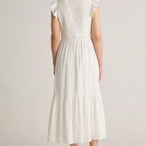 เดรสยาวปานกลางสีขาวแฟชั่นใหม่ขายดีสำหรับผู้หญิง ผ้าฝ้ายแท้ 100% ลายเรียบ คอวีทรงสโมค ใส่สบายสำหรับฤดูร้อน - Product Image 4