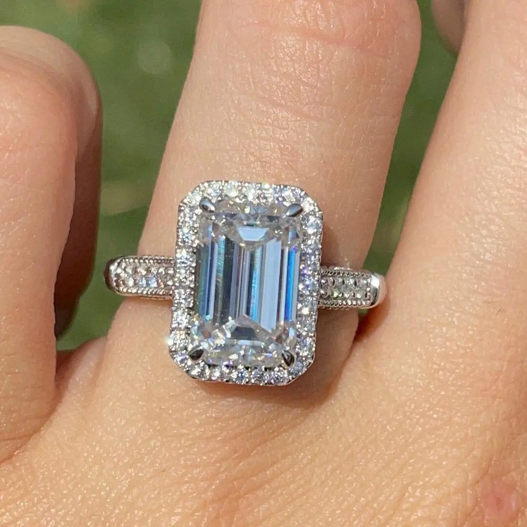 Elongated 7x11mm emerald cut moissanite ring set in 14k white gold with a halo and vintage style filigree accents jewelry