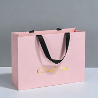 Sac promotionnel écologique en papier kraft rose avec logo personnalisé en feuille d'or et poignées en ruban noir pour boutique de vêtements