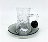Ensemble de tasses à café en verre borosilicate martelé à forme cintrée, avec poignée boule noire, forme sablier texturée, et soucoupe gris fumé classique pour le thé