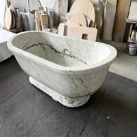 Baignoire autoportante ovale en marbre blanc avec rebord large et base sculpturale pour villas et hôtels