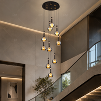 Lustre en cascade avec globes en verre gris fumé, ampoules dorées, cordons noirs, en fer et verre, éclairage moderne et élégant pour escalier de villa