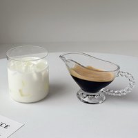 Carafe à crème en verre transparent avec poignée perlée et base sur pied, verseuse à lait pour le service de café et de thé sur table