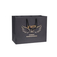 Sac en papier noir enduit de poignées de ruban intégrées avec logo en feuille d'or imprimé de luxe