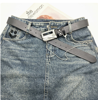 Cette ceinture noire unique est de style rétro avec un pendentif en cuivre de type pager, marquée 'STAY AHEAD ADVISOR' et décorée d'une délicate chaîne à billes suspendue.