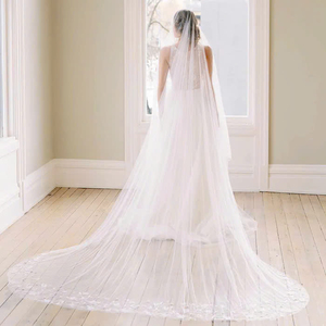 Un impresionante velo de longitud Catedral hecho de tul suave, adornado con intrincados adornos de encaje y diseñado con un cómodo peine. - Product Image 1