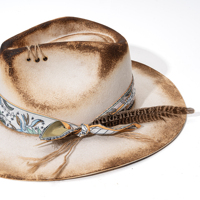 Topi koboi wanita dari wol felt 100% buatan tangan, dengan aksen usang bergaya western, dilengkapi pita syal bunga dan bulu.