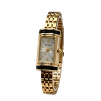 Montre élégante pour femme avec bracelet en acrylique, finition dorée, design cylindrique style cadenas, style médiéval élégant, mouvement à quartz léger