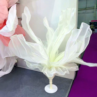 Grande fleur géante en tissu organza blanc, sur pied, pour la décoration d'allées de mariage et de scènes.