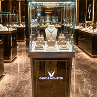 Présentoir sur pied en verre recyclable et écologique avec finition miroir personnalisée, éclairage LED et logo sur mesure pour bijouterie, horlogerie et showroom de marques.