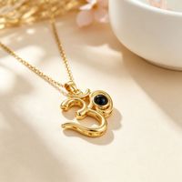 Colliers de projection personnalisés en cuivre plaqué or avec zircon 2026 Pendentif commémoratif personnalisé avec symbole OM pour unisexe