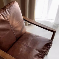 Fauteuil d'appoint en cuir et noyer de style Mid-Century, avec coussin marron à points de couture et rembourrage haute résilience, idéal pour salon ou coin lecture.