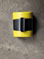 Barrière de guidage murale rétractable avec bande de signalisation noire et jaune pour la gestion des files d'attente et la régulation du trafic