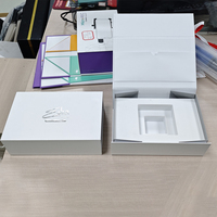 Boîte en carton rigide blanche de luxe avec logo argenté en forme de livre Coffrets cadeaux magnétiques pliants Insert en mousse EVA Stratification mate de crème pour le visage