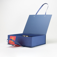 Boîte cadeau de Noël et du Nouvel An bleue, orange et rouge en papier couché avec pelliculage brillant et mat, gaufrage et estampage pour bougies