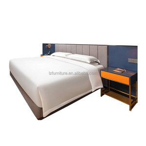 Ensemble de meubles de chambre d'hôtel, lit moderne en bois capitonné avec tête de lit intégrée en tissu et tables de chevet pour hôtel 3 étoiles - Product Image 1