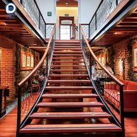 Escalier en L vintage personnalisé Prima en pierre noire avec main courante en bois foncé et balustres en fer ornés de laiton pour manoir classique