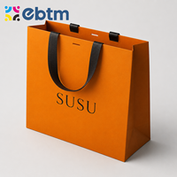 Sacs cadeaux en papier orange de luxe personnalisés en gros avec poignées en ruban noir pour l'emballage de détail