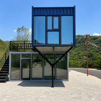 Maison préfabriquée contemporaine en conteneur à deux étages, avec toit en pente imitation bois, mur entièrement vitré et design cantilever.