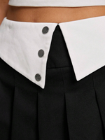 Jupe mini plissée taille haute noire pour femme avec revers contrastant, détail boutonné, style preppy, coupe trapèze