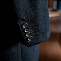 Manteau long en laine pour homme noir mat, col large, tissu dense et lisse, composition inhérente raffinée pour les environnements professionnels