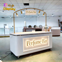 Comptoir de bar à parfums moderne de luxe avec éclairage LED personnalisé, panneau cannelé blanc, cadre doré pour les magasins de cosmétiques et les centres commerciaux