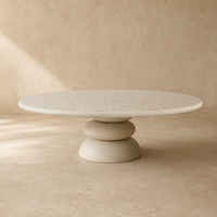 Table basse de luxe en travertin blanc, plateau rond en marbre naturel avec motif gravé, sur piétement colonne en galets empilés