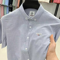 Kemeja Pria Lengan Pendek Biru Muda, Model Kasual Oxford Kancing Depan dengan Bordir Kecil Gaya Minimalis