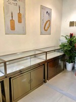 Vitrine de magasin de bijoux personnalisée en acier inoxydable, bois et verre avec un design tendance pour l'affichage de colliers, boucles d'oreilles et bagues