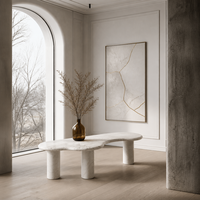 Table basse moderne en travertin beige naturel de forme organique Wabi Sabi, avec 3 pieds cylindriques incurvés irréguliers, finition mate en pierre
