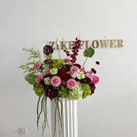 Centre de table personnalisé pour mariage avec fleurs de lys Calla bordeaux, fleurs vert sauge pour la mariée, coussin décoratif, scène extérieure