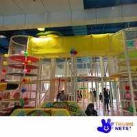 Structure de grimpette intérieure multi-niveaux en filet blanc avec poteaux rembourrés et plateformes colorées – Équipement commercial pour centre de jeux pour enfants