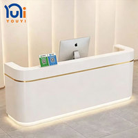 Comptoir d'accueil minimaliste en marbre courbé avec éclairage LED inférieur et finition dorée pour bureau, hôtel, spa, hall d'entrée